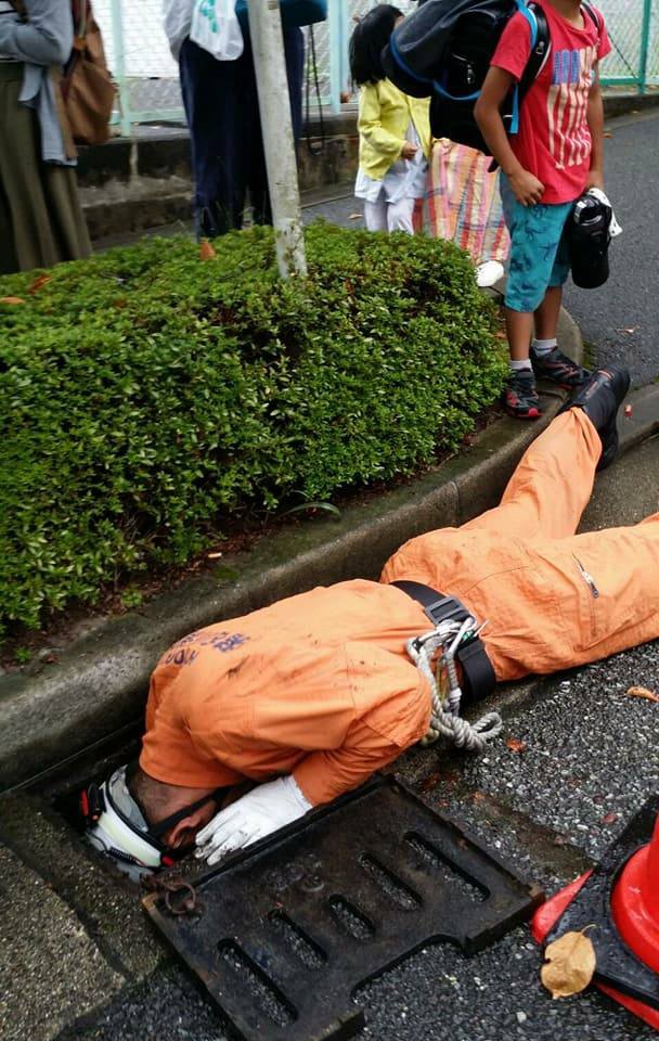 マンホールをのぞく消防士さん