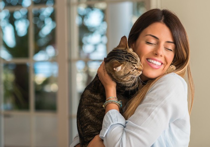 女性に抱かれて顔を近づける猫