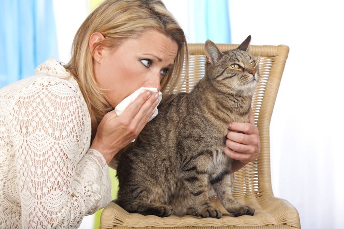 鼻をおさえる女性と猫