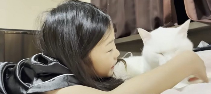 ベッドの上に寝転ぶ子どもと猫