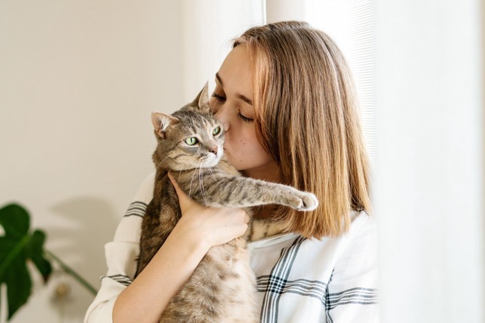 抱いている猫にキスをする女性