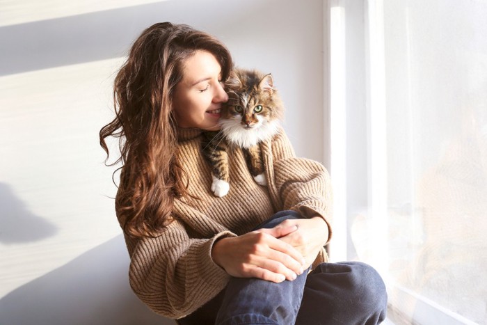 窓辺でくつろぐ女性と猫