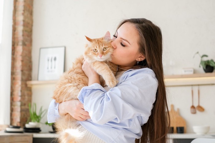 抱っこした猫にキスをする女性