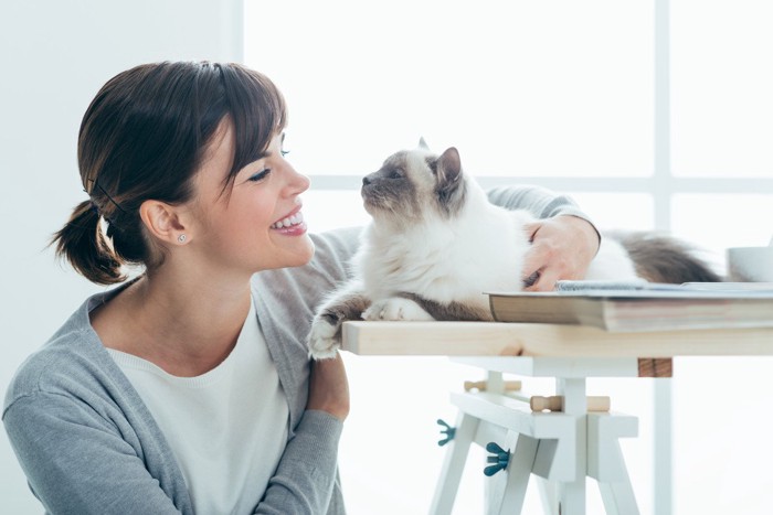 笑顔で見つめ合う女性と猫