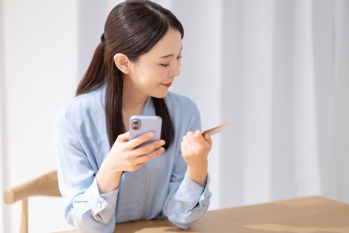 スマホと写真を見ながら微笑む女性