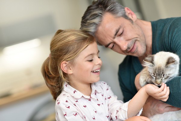 男性にだっこされる猫と子供