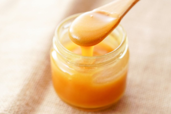 ガラス瓶に入ったマヌカハニーをすくっている様子