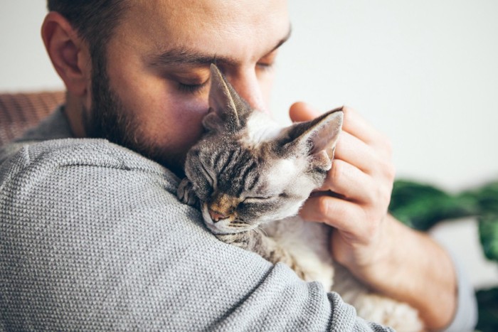 お互いに抱き合う猫と飼い主