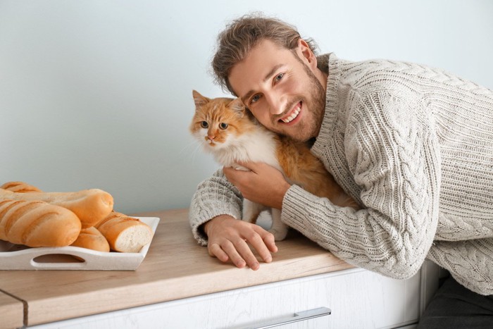 男性に抱き着かれて嫌そうな猫