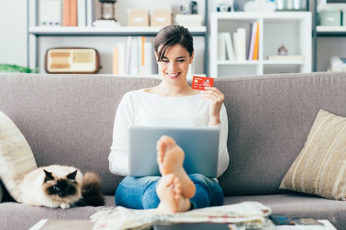 ネットで買物をする女性と隣で寛ぐ猫