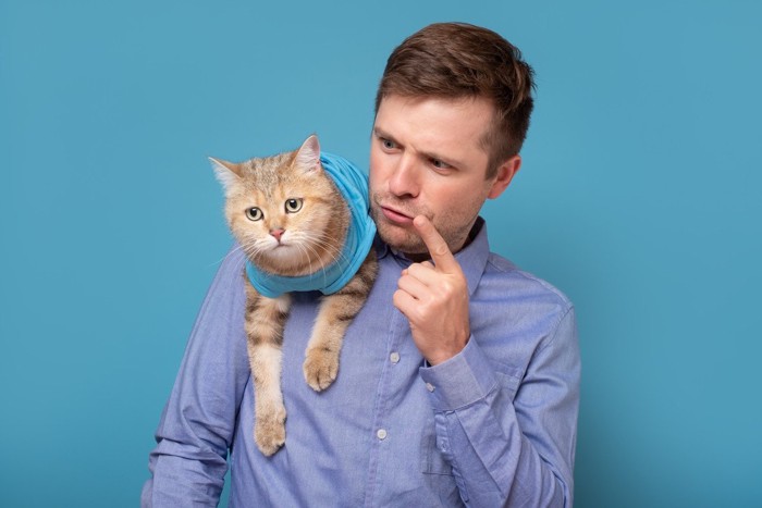 肩の上の猫を叱る男性