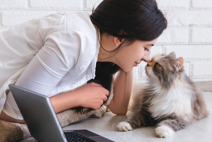 鼻を付け合う女性と猫