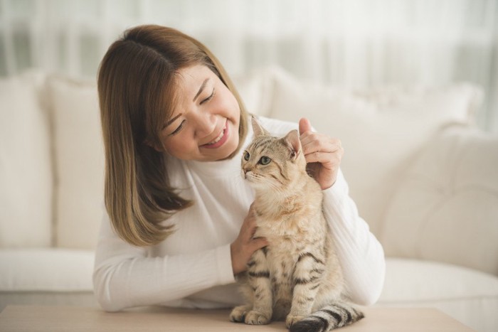 後ろから猫を見る女性