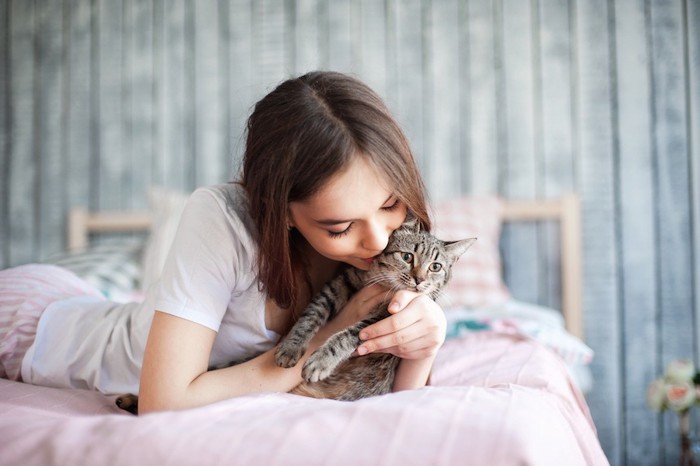 ベットで猫にキスをする女性