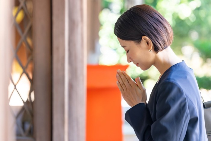 神社で願い事をする女性