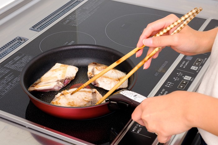 フライパンでブリの切り身を焼いている様子