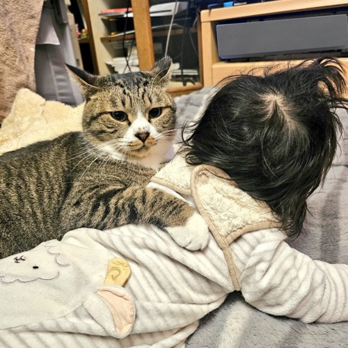 赤ちゃんの背中に前足を乗せる猫
