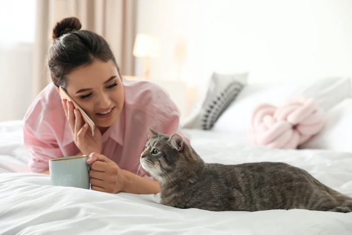 電話をしながら猫と同じ体勢になっている女性