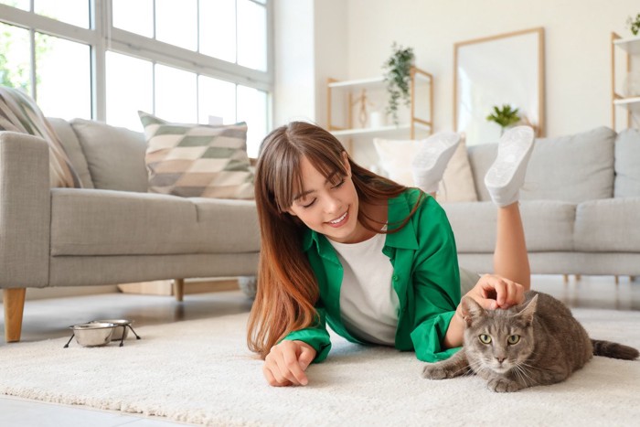 グリーンのシャツの美女に撫でられている猫