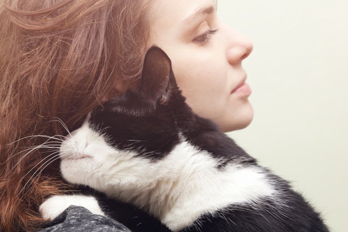 女性に抱っこされるシロクロ猫