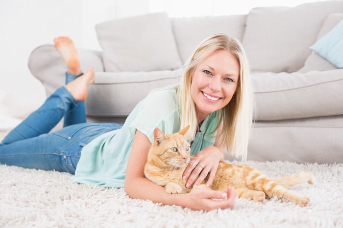 カーペットの上でくつろぐ女性と猫