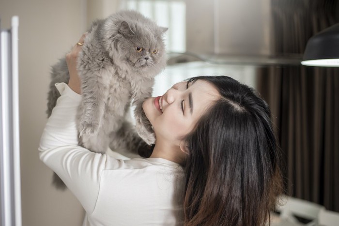 女性に抱き上げられて嫌そうな猫