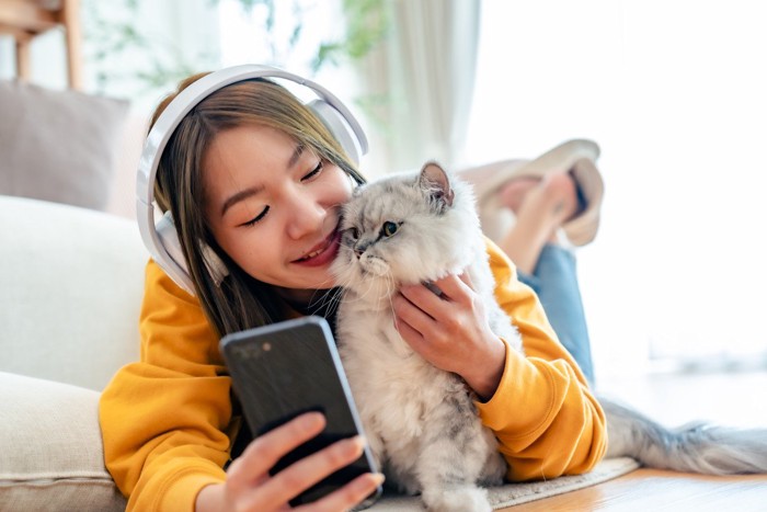 ヘッドホンをする女性と猫