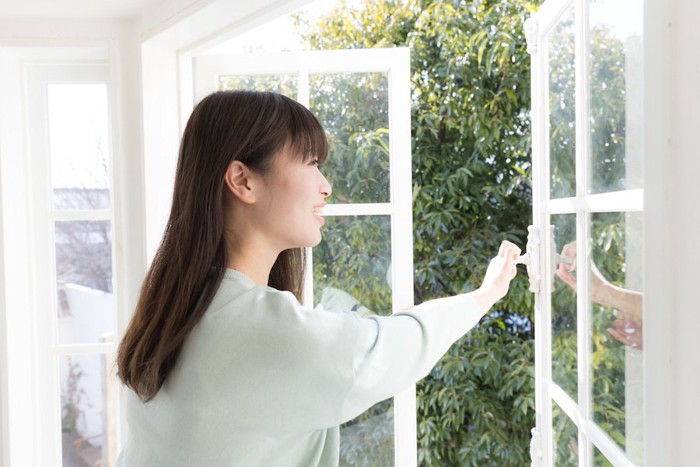 部屋の窓を閉める女性