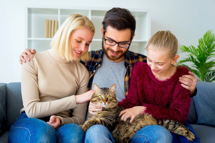 家族と男性の膝に乗る猫