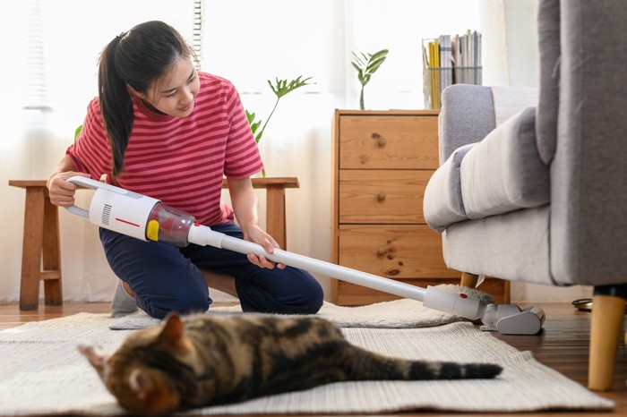 ソファの下を掃除する女性