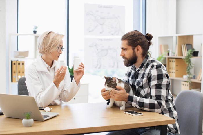 動物病院で相談中の男性と猫