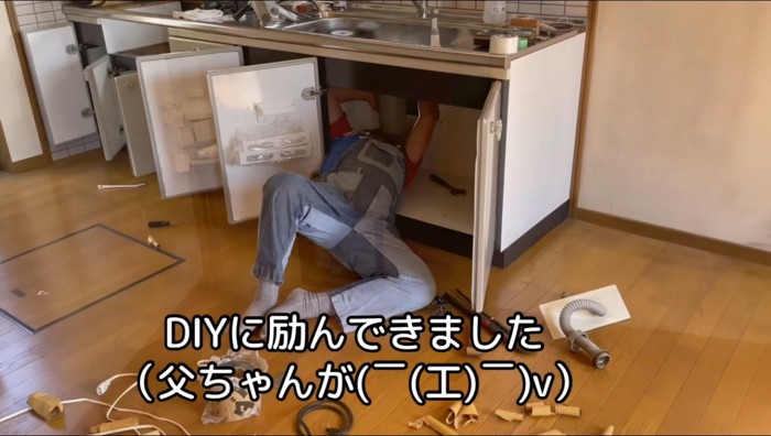 シンクの下で仰向けになって作業する男性