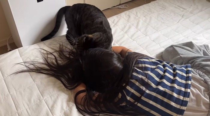 倒れる真似をしている女の子と猫