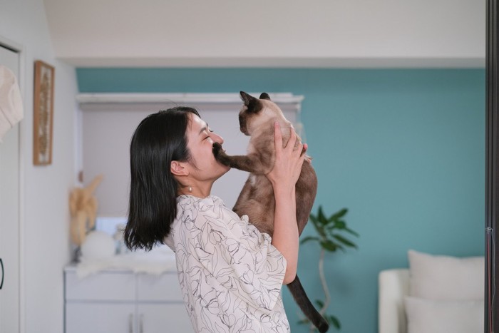 女性の顔を手で押さえる猫