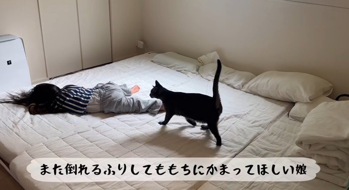 倒れる真似をしている女の子と猫