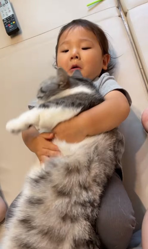 猫を抱えて寝転がる男の子2