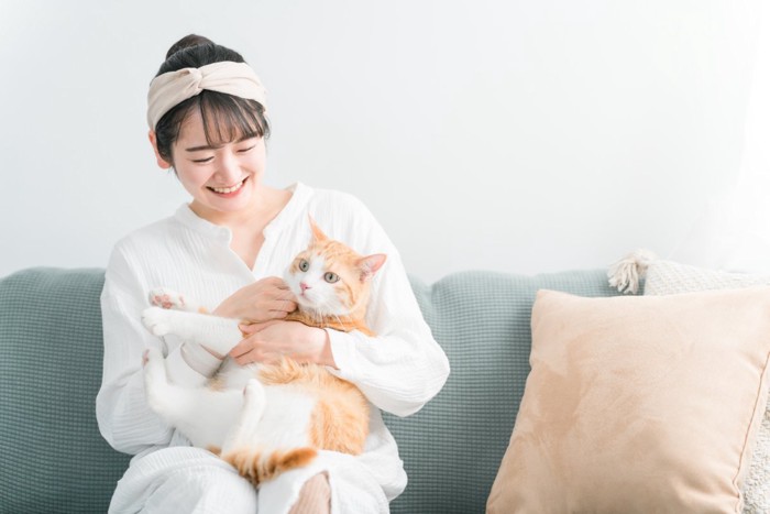 猫を膝の上で撫でる女性