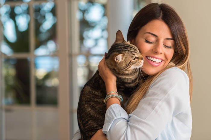猫を抱きしめて笑う女性