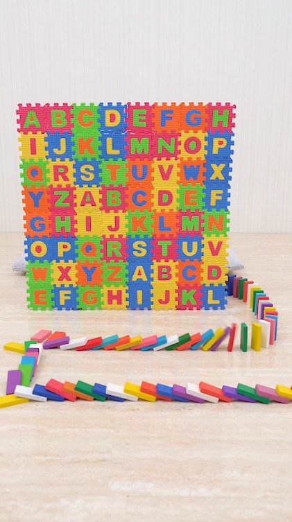 英語がかかれたボードに向かって倒れていくドミノ