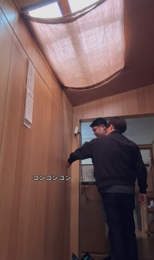 壁をノックする2人の男性