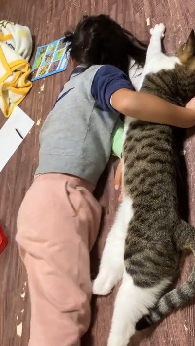 猫を抱いて横になる子ども