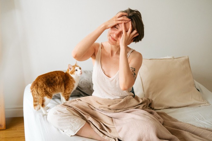 飼い主の女性を起こす猫