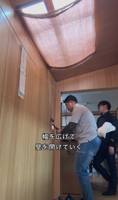 長方形に開いた壁の穴を広げている男性