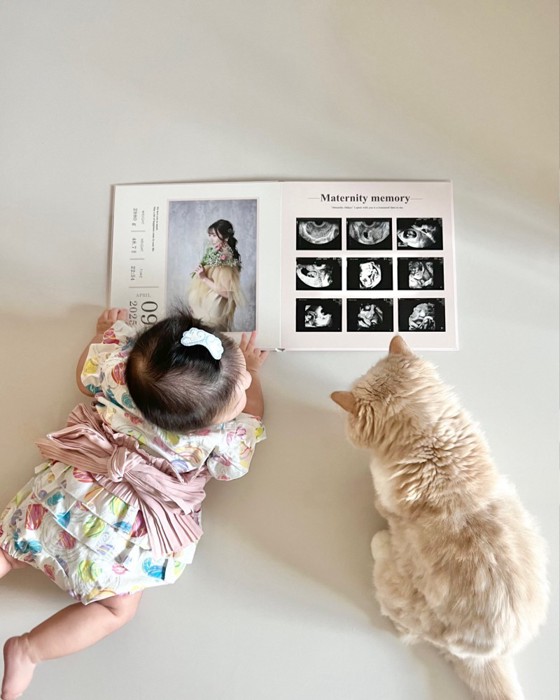 並んでアルバムを見る赤ちゃんと猫