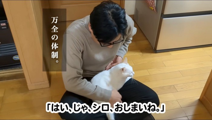 膝の上から猫を降ろす男性