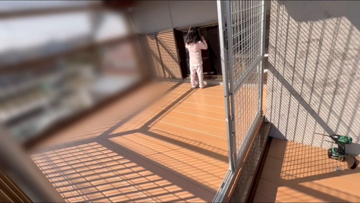 ウッドデッキから家の中を覗く女の子