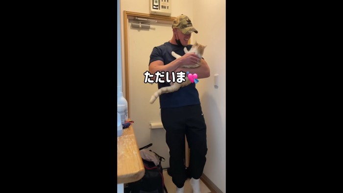 玄関で抱っこされる猫