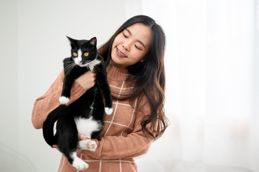 アジア人学生に抱かれる白黒猫