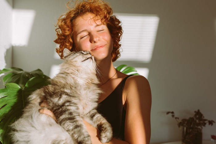 女性の顔にスリスリする猫