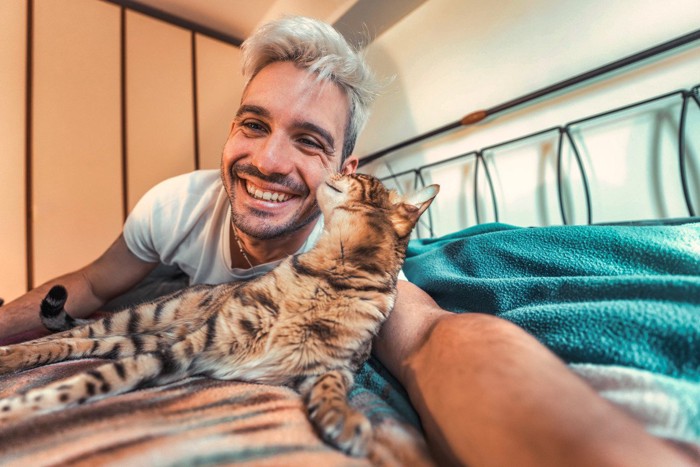 ベッドで愛猫とコミュニケーションを図る男性